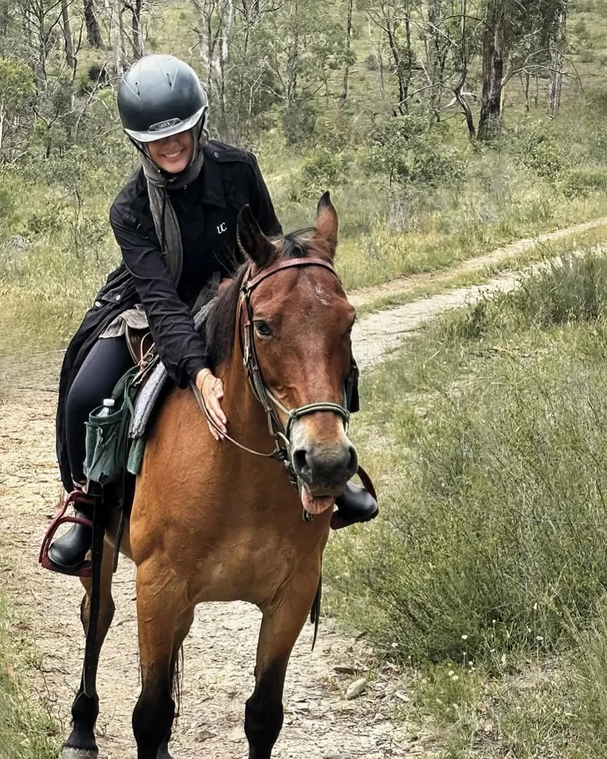 Amy smiling on horseback on a bush trail