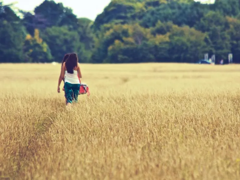 A woman walking a path through a sunlit field